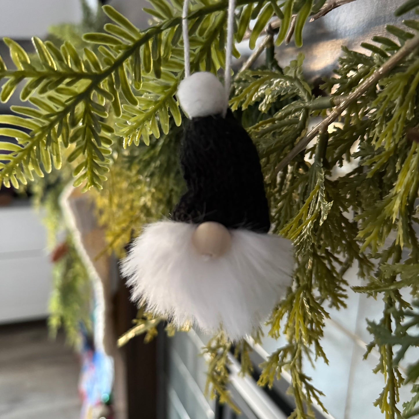 Decorative gnome ornament hanging on a green leafy branch