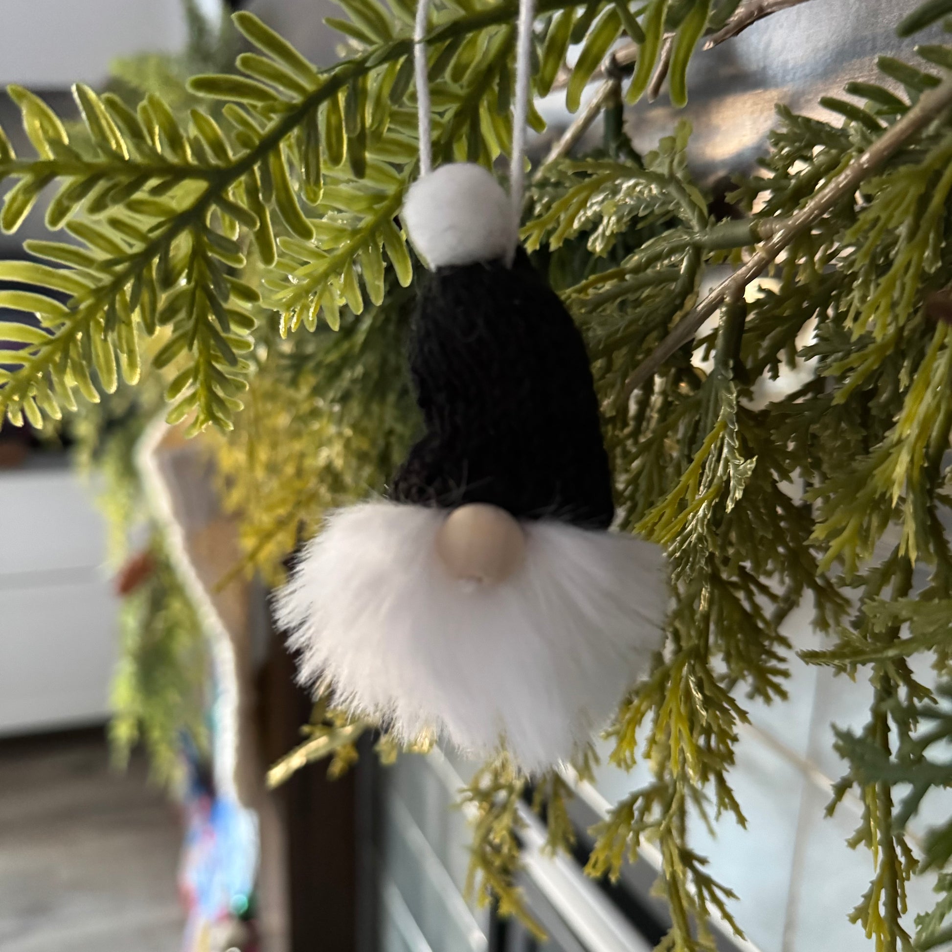 Decorative gnome ornament hanging on a green leafy branch